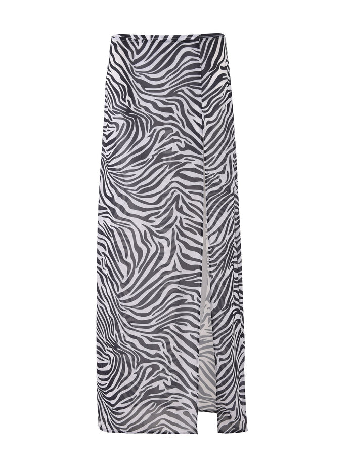 The AYESHA SKIRT - BLACK: ZEBRA from TIGERMIST showcases a black and white zebra print pattern. This long skirt features a straight design with a subtle slit on the front right side.