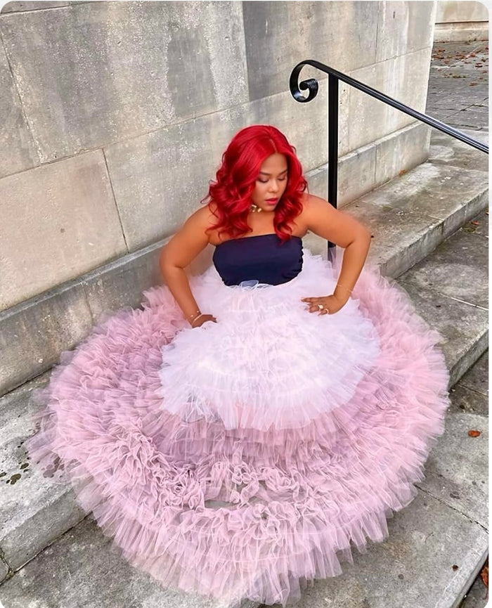 Woman in a pink ruffled skirt sitting on stone steps.
