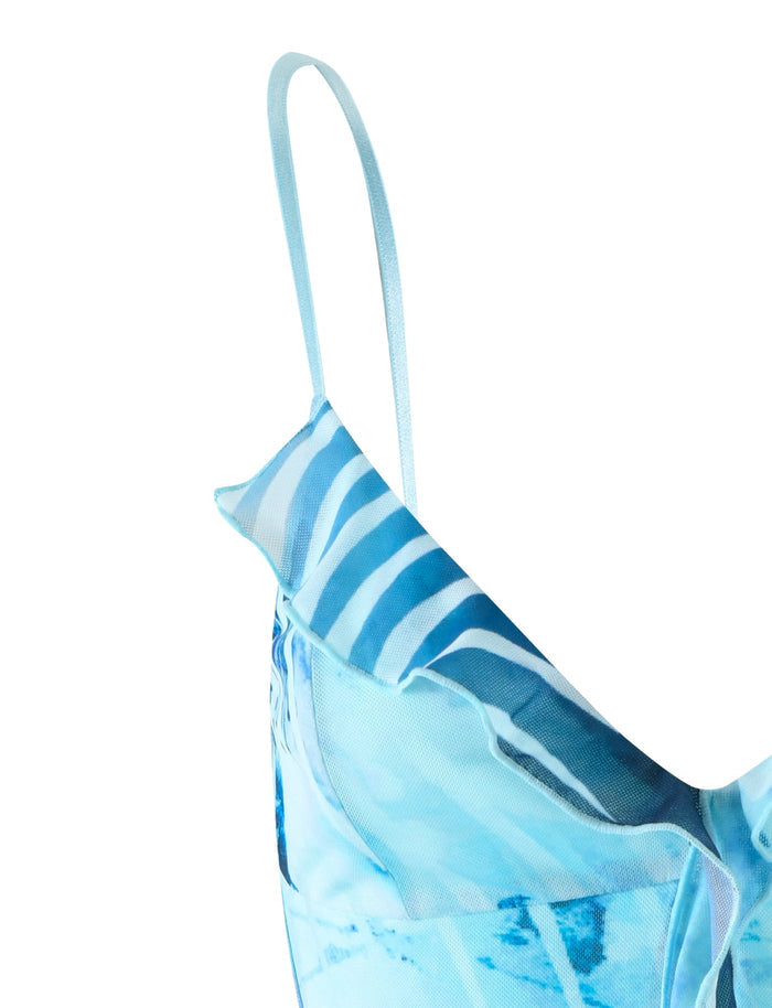 Close-up of the CARLY DRESS in BLUE : FLORAL WAVE from TIGERMIST, showcasing a ruffled shoulder detail and thin spaghetti straps. The design includes abstract blue ocean waves and white stripes, creating a dynamic and flowing look.