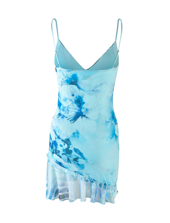 Introducing the CARLY DRESS - BLUE : FLORAL WAVE by TIGERMIST, a sleeveless dress featuring thin spaghetti straps and a ruffled hem. The dress showcases a striking mix of light and dark blue patterns in an abstract floral wave design. Its asymmetrical hem adds dynamic flair to the flowy fabric, making it the perfect choice for any stylish outing.