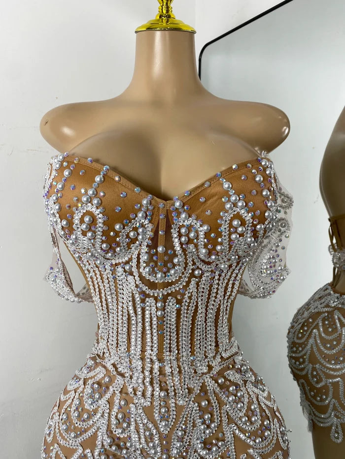 Shine in the Claren pearl and rhinestone off-the-shoulder mesh bodycon mini dress. Perfect for birthdays, parties, and special occasions.