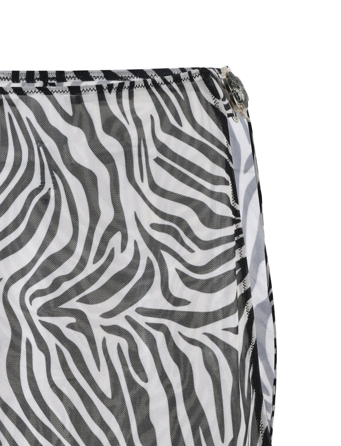 Close-up of the CYNTHIA MINI MESH SKIRT - BLACK : ZEBRA fabric by TIGERMIST, showcasing a black and white zebra print pattern. The skirt features stripes that mimic a zebra's coat, with visible black stitching along the edge and a partially visible metal zipper on the right side.