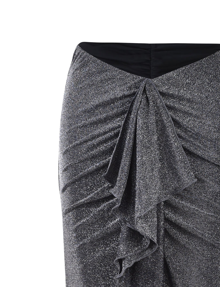Close-up of a TIGERMIST DAISIE SKIRT - BLACK : BLACK SHIMMER with a textured, sparkly fabric. The skirt features ruching at the sides and a cascading ruffle detail down the front. The waistband is black and the garment has a fitted silhouette.