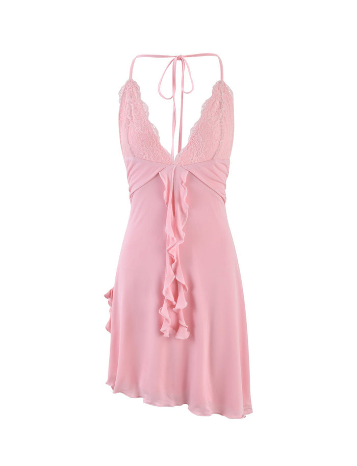 A DEENA DRESS by TIGERMIST in baby pink, featuring lace detailing on the bodice, spaghetti straps that tie at the back, and a ruffled front design. The silky, lightweight fabric offers a slightly flared hem.