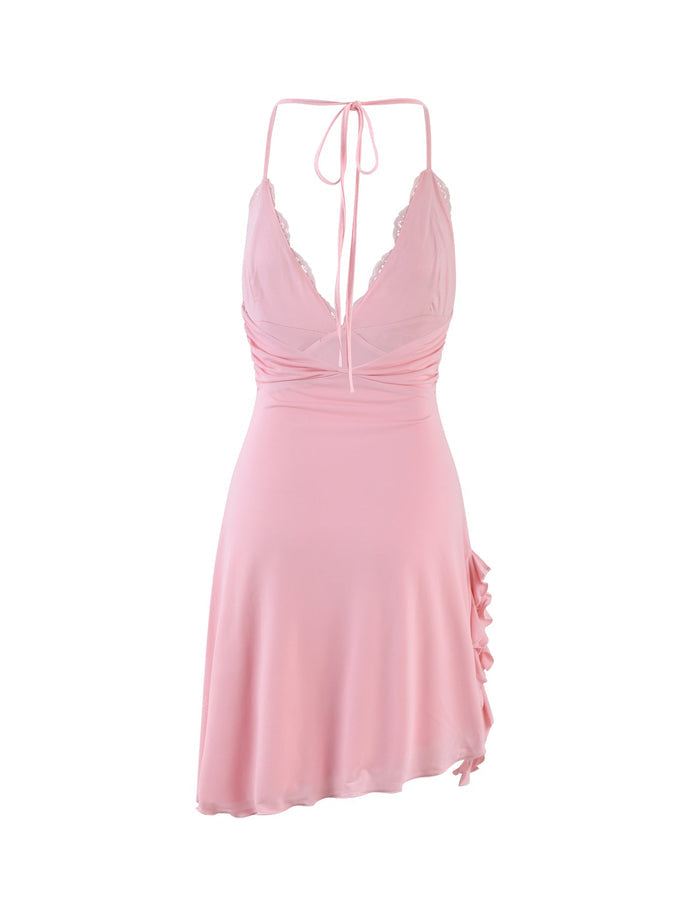 The DEENA DRESS - PINK: BABY PINK from TIGERMIST is a light pink satin slip dress with a deep V-neckline, thin halter straps that tie at the neck, and lace trim along the bust. It features a fitted waist and a short, flowing skirt with ruffle detail on one side, creating an elegant and delicate look.