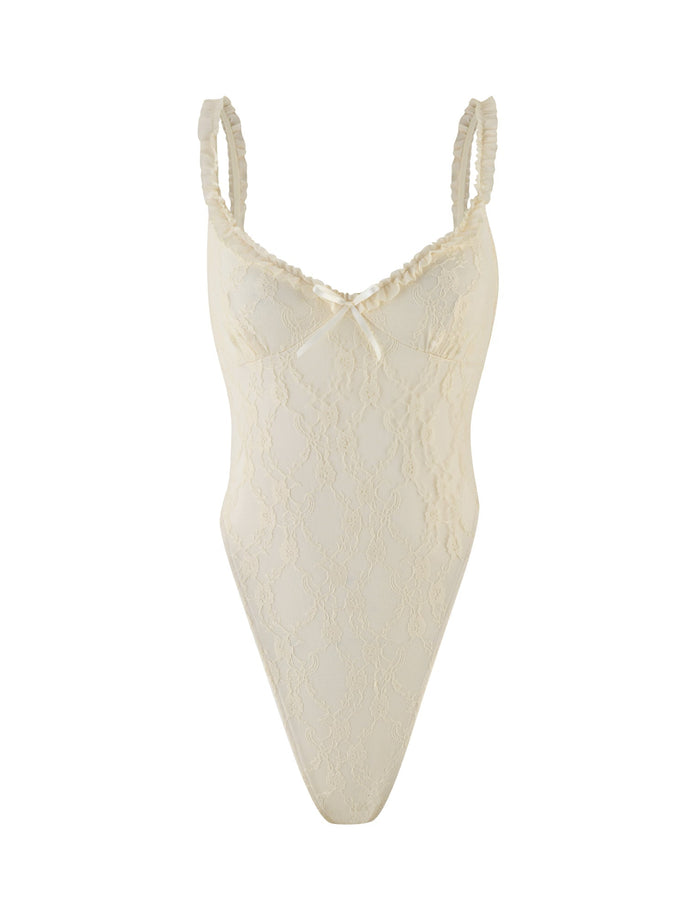 The TIGERMIST DEJA BODYSUIT features champagne lace in beige, thin ruffled straps, a center bow on its sweetheart neckline, and a delicate semi-sheer floral design.