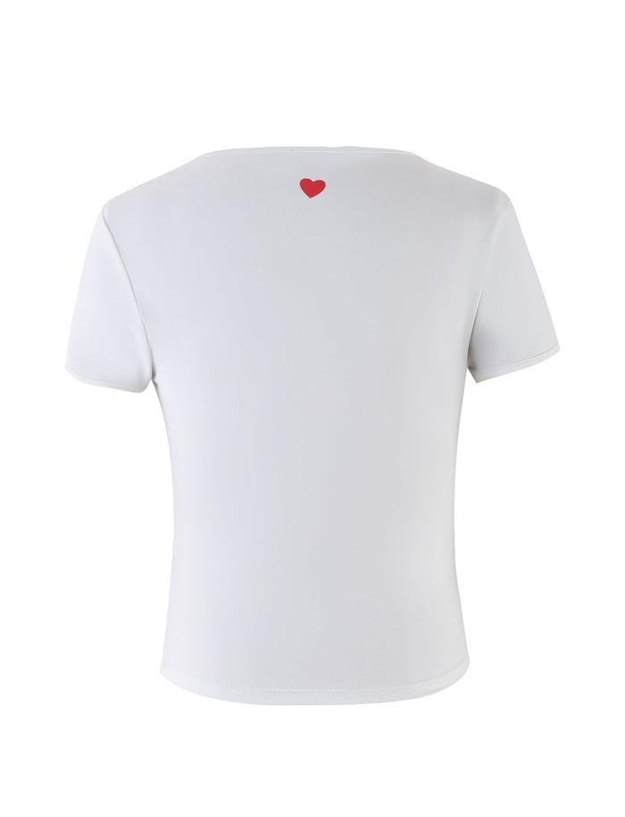 The DELANEY TEE - WHITE from TIGERMIST is a plain white short-sleeve t-shirt, featuring a small red heart printed near the neckline on the back. The shirt is displayed against a white background.