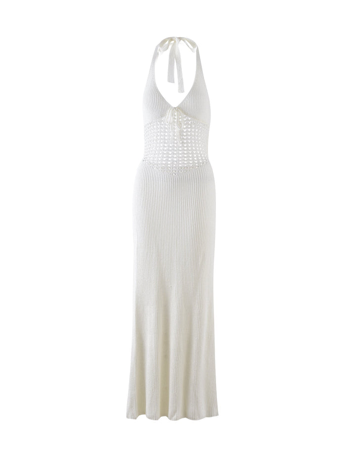 The DELTA DRESS - WHITE from TIGERMIST is a sleeveless, halter neck maxi dress featuring a deep V-neckline and intricate crochet detailing around the bodice. The dress showcases a fitted, ribbed knit design that flares slightly at the hem.