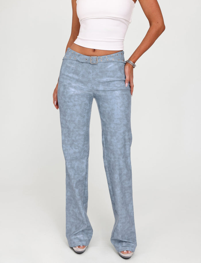 A person wearing a white crop top from Tiger Mist, light blue EMERSYN PANT - BLUE : DUSTY BLUE from TIGERMIST, and silver open-toe heels stands in a neutral pose with their right hand on their hip, in front of a plain white background.