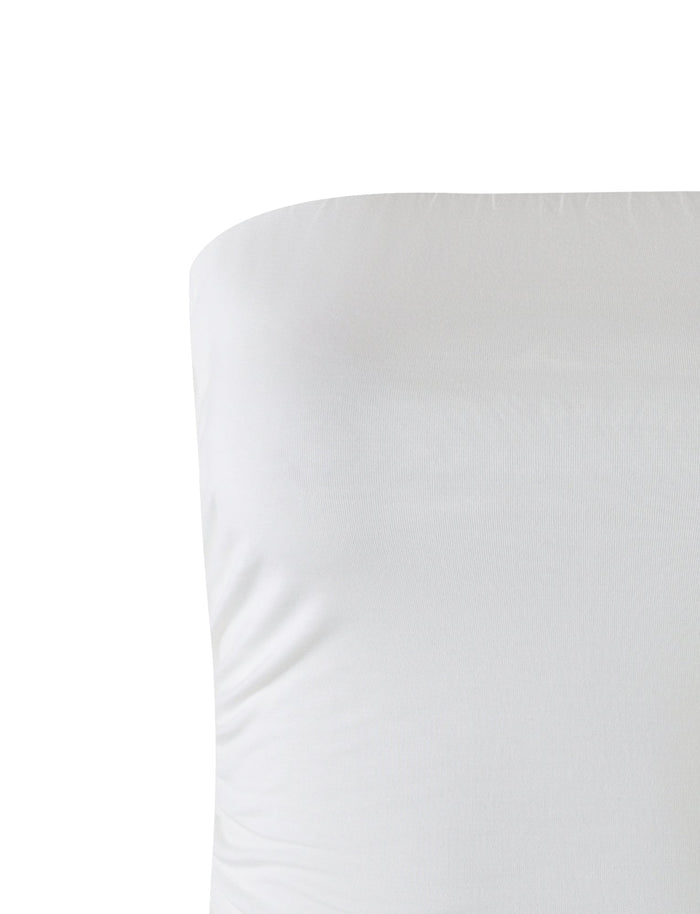 A close-up shot of the white, form-fitting HARRIETT JERSEY TUBE TOP from TIGERMIST. The smooth texture of the fabric exhibits gentle folds and a plain appearance against a white background, making the tube top the main focus of the image.
