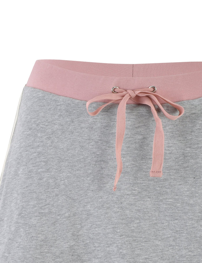 Close-up of the waistband of a pair of light gray skorts. The waistband is pink with metal grommets and features a pink drawstring tied into a bow. These TIGERMIST JAYLEE SKORTS have a comfortable, casual look.