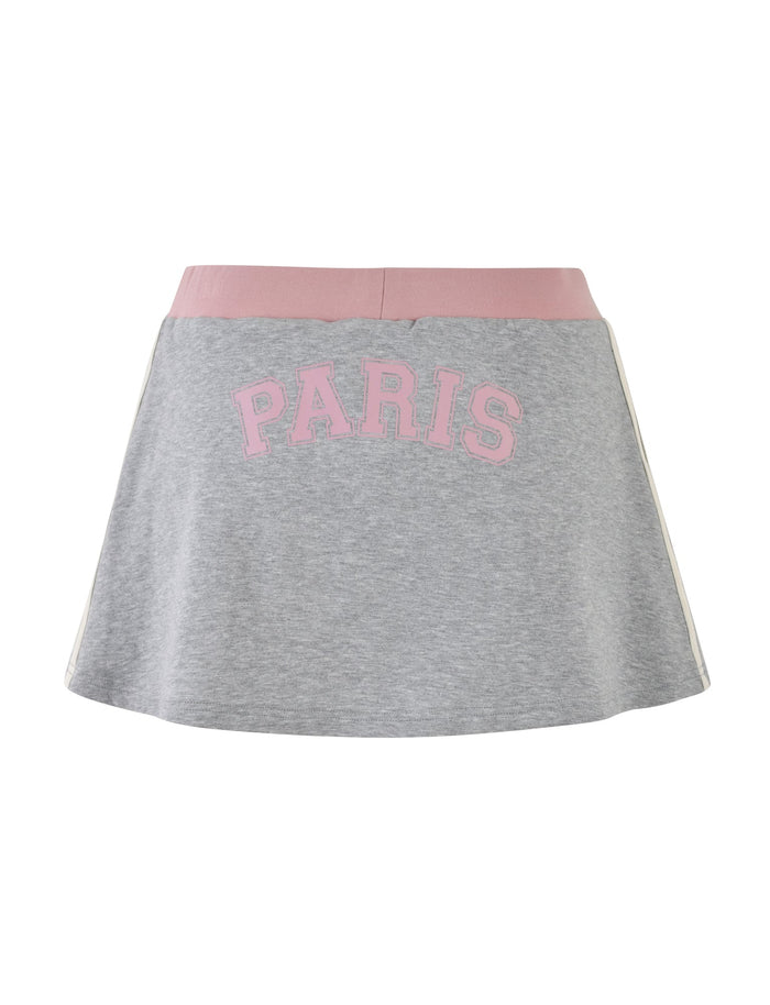The JAYLEE SKORT - GREY from TIGERMIST features a pink waistband and has "PARIS" printed in large, pink, capital letters across the front. It is finished with white vertical stripes along the sides for a chic look.