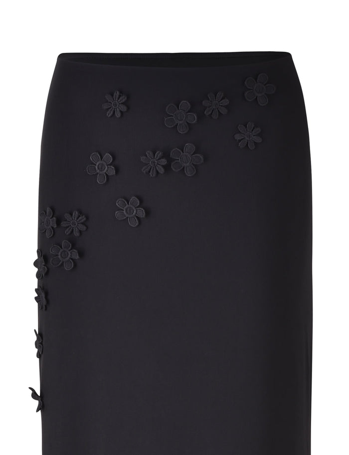 The KATINA SKIRT - BLACK from TIGERMIST features decorative black floral appliqués scattered across the front and side. The three-dimensional flowers add texture to the sleek design of this midi skirt, which is tapered at the waist for a fitted and elegant look.