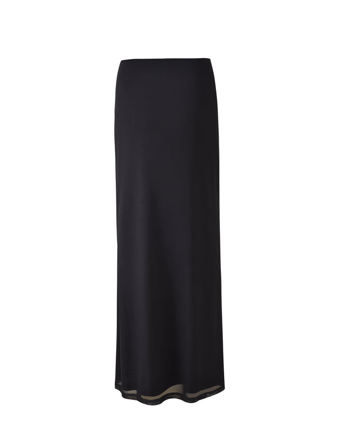A long black "KATINA SKIRT - BLACK" from TIGERMIST is displayed on a plain white background. The skirt features a straight silhouette with a smooth texture and minimalist design. The bottom hem has a slight curve with subtle detailing, making the lightweight material flowy and elegant.