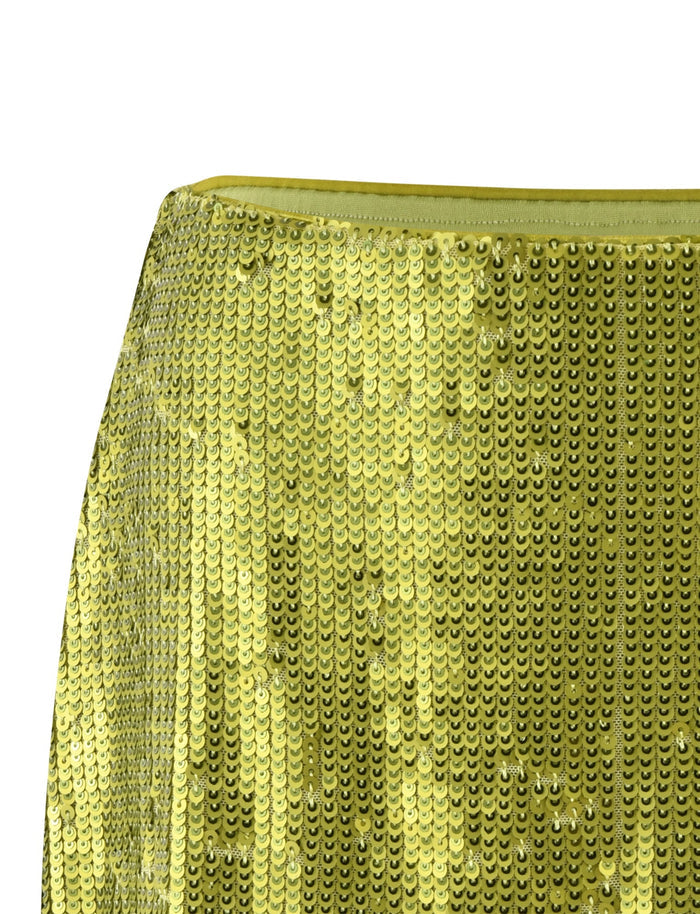 A close-up image of a green sequin fabric from TigerMist's Kaye Skirt. The sequins create a shimmering effect, reflecting light and showcasing a textured, shiny surface. The fabric appears to be part of the Kaye Skirt garment.