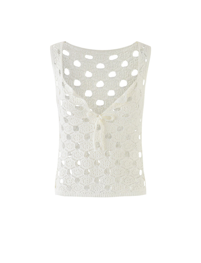 The KINCADE TOP in white by TIGERMIST is a crocheted sleeveless top that features a deep V-neckline and a small tie closure at the front. The design showcases large, circular openwork details throughout, giving it a lightweight and airy feel.