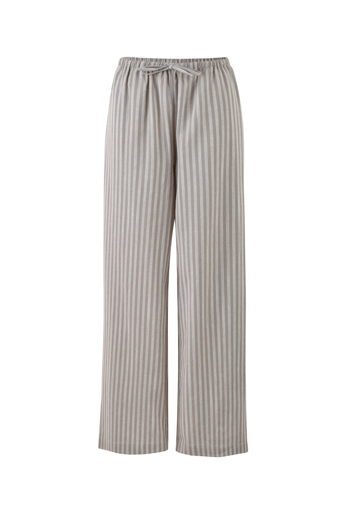 The LAINEY PANT in Grey Stripe by TIGERMIST is a pair of loose-fitting, high-waisted pants with a light beige and white vertical stripe pattern. Designed for comfort and style, these pants feature an elastic waistband with a drawstring and wide legs for a casual look.