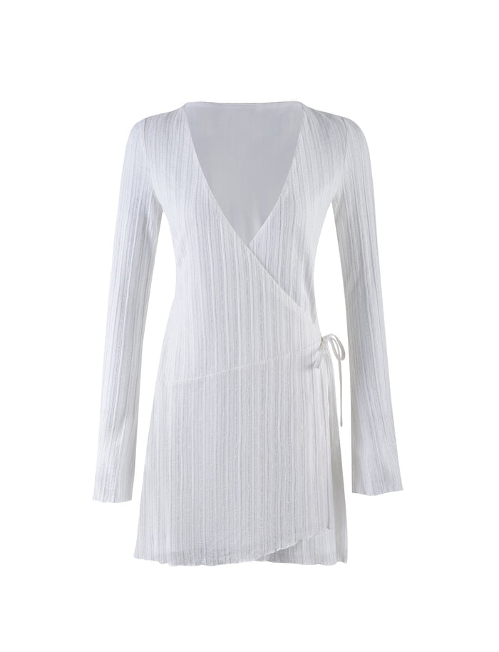 The LEVINS DRESS - WHITE from TIGERMIST is a wrap-style, long-sleeve dress with a v-neckline and an asymmetric hemline. It features a tie detail on the right side for closure and has a subtle, textured, vertical stripe pattern. The design is minimalistic and elegant.