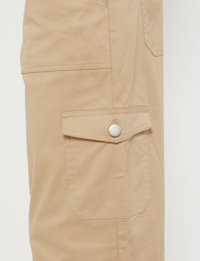 Close-up of a pair of beige LISSA PANT from TIGERMIST, focusing on the side pocket. The TIGERMIST pocket has a flap secured with a metal snap button and is neatly stitched. The fabric appears to be durable and suitable for outdoor activities or workwear. The background is plain white.