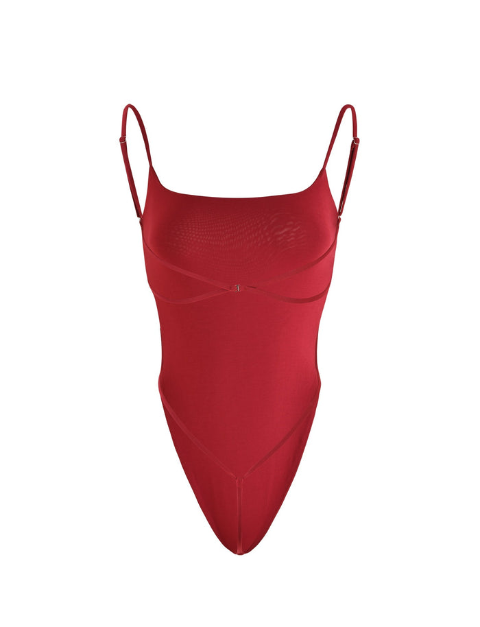 The MINERVA BODYSUIT - RED from TIGERMIST is a sleeveless bodysuit with thin, adjustable spaghetti straps and a rounded neckline. It boasts a form-fitting design with asymmetrical seam detailing. The smooth and stretchy fabric is ideal for intimate or fashion wear.