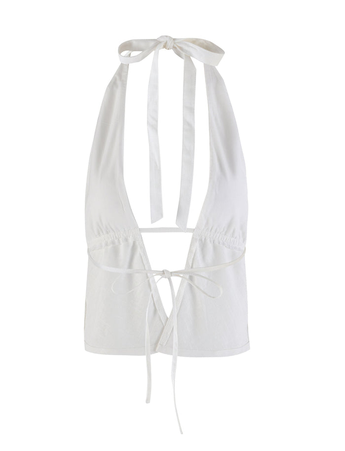 The NICOLA TOP - WHITE by TIGERMIST is a stylish halter top featuring a plunging neckline and a tied back design. It boasts adjustable straps that tie at the neck and an additional tie around the lower back for a secure fit. The lightweight fabric makes it perfect for warm weather.