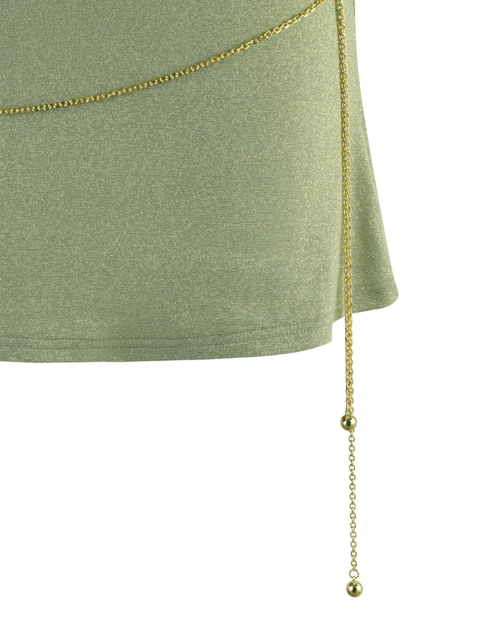 A close-up of the TIGERMIST OPELI DRESS - GREEN SPARKLE, a light green mini dress with a thin gold chain belt draped diagonally at the waist and finished with a dangling chain adorned with small gold beads.