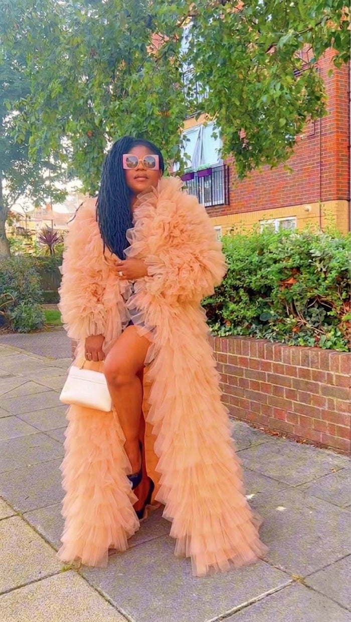 Woman wearing a peach ruffled coat in an outdoor setting