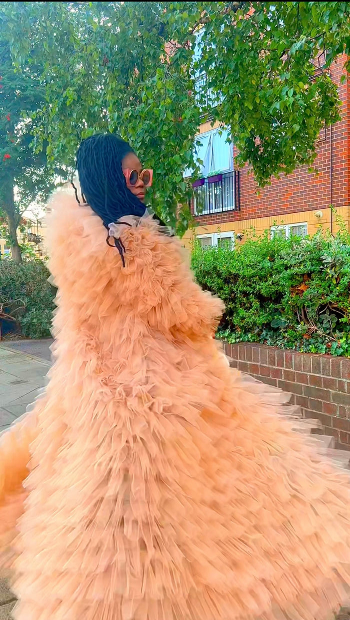 Person wearing a peach feathered dress with a blurred background