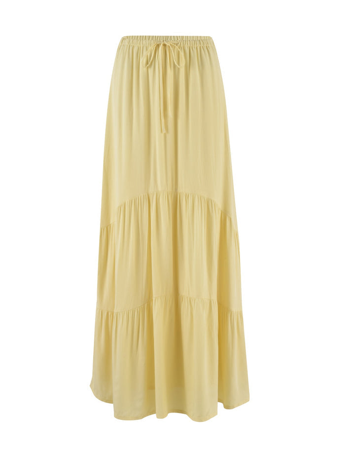 The PHILLIPA SKIRT - YELLOW : LEMON by TIGERMIST is a light yellow, ankle-length skirt with an elastic waistband and drawstring tie. This design features a relaxed fit with tiered layers that add volume and texture.