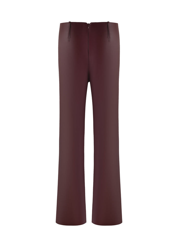 Introducing the PU Teddie Pant in Cherry Red from TIGERMIST—a pair of high-waisted, wide-leg trousers crafted from deep burgundy fabric. These trousers feature a zipper closure at the back and boast a smooth finish, likely made from satin or a synthetic blend. The design is minimalist with no visible pockets or embellishments.