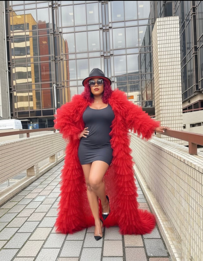 Woman wearing a red fur coat and black dress on a rooftop with cityscape background