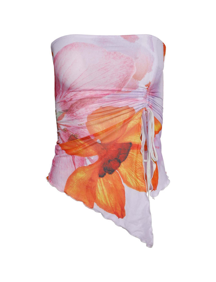 The Sariah Top - Multi: Macro Floral by Poppy Summer from TIGERMIST is a strapless, asymmetrical top with a ruched front featuring large, vibrant flowers in pink, orange, and yellow hues set against a predominantly white background. A decorative tie detail adorns the side.