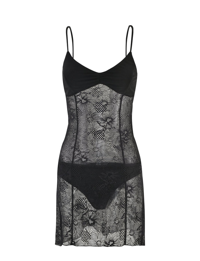 The SASKIA DRESS - BLACK from TIGERMIST is a black lace lingerie slip dress with thin spaghetti straps and a fitted, semi-transparent floral lace design. This dress features a plunging neckline and extends to mid-thigh length.