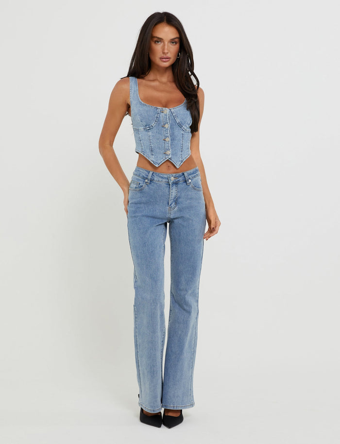 A woman with long dark hair models a sleeveless TIGERMIST denim corset top paired with TATYANA JEANS - BLUE: LIGHT WASH : LIGHT DENIM high-waisted straight-leg jeans. She is standing against a plain white background, wearing black pointed-toe shoes.