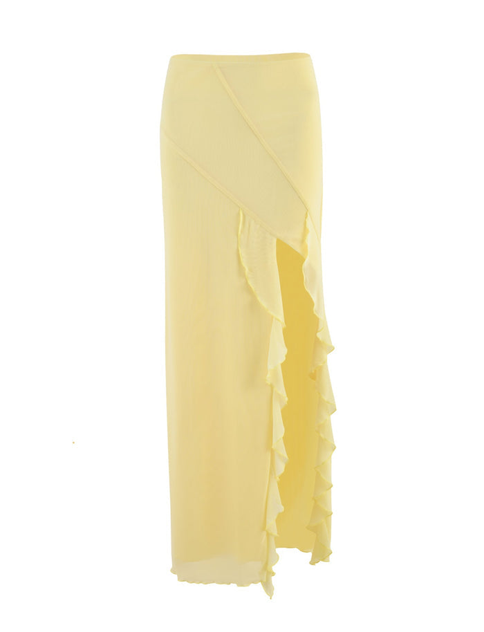 The TIGERMIST THEO SKIRT in the vibrant LEMON shade boasts a wraparound design with a high slit on the left side, adorned with cascading ruffles for an elegant touch. Made from lightweight fabric, this yellow maxi skirt offers a flowy and airy appearance.
