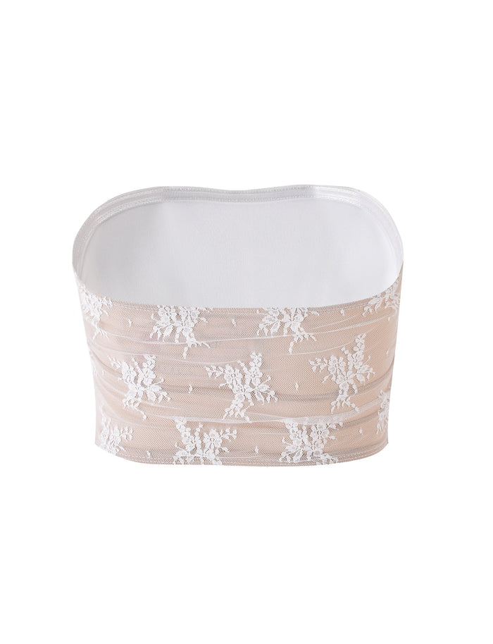 The TIANNA TOP - WHITE from TIGERMIST is a beige strapless lace bandeau adorned with white floral embroidery. It features a sheer outer layer over an opaque lining, with smooth, elastic top and bottom edges. Displayed on a plain white background, the intricacies of the design are highlighted beautifully.