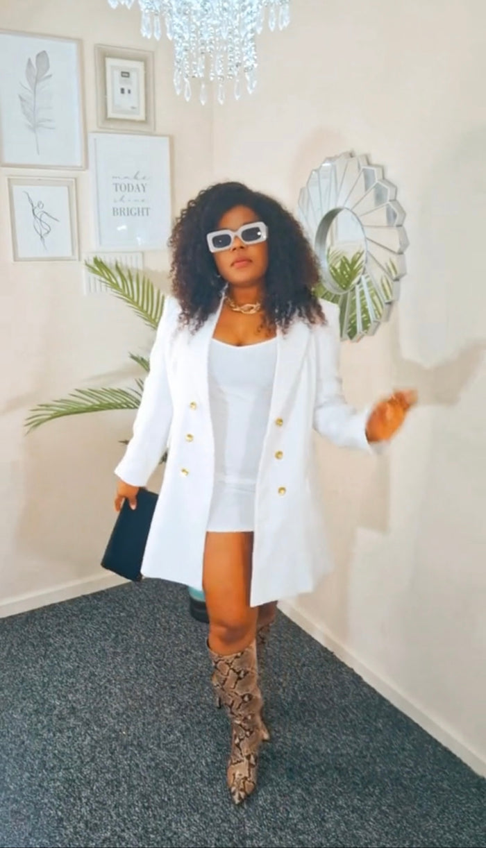 Woman in a white outfit with a short coat in an indoor setting